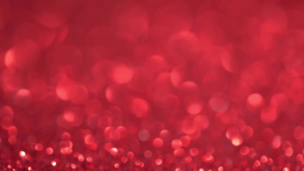Streszczenie tła czerwonego brokatu z ruchomymi i migoczącymi cząstkami. Magiczny pył, metalowe cekiny, błyszcząca faktura, światła wakacyjne, latające cząsteczki tworzą piękny bokeh. Świecące tło świąteczne — Wideo stockowe