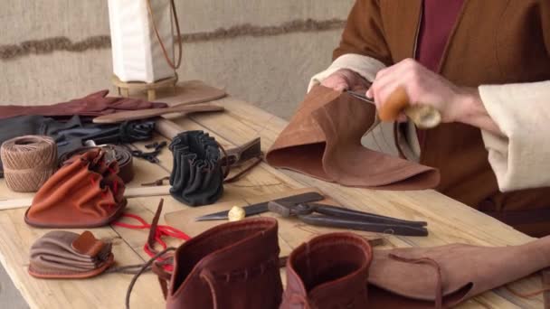 Oficina histórica de couro europeu. Trabalhadores de couro da escuna medieval artesãos. Artesanato cose à mão uma carteira, sapatos, cinto, luvas. — Vídeo de Stock