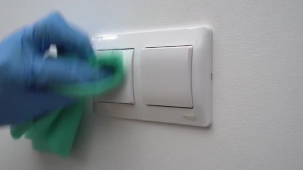 Ein Putzmann mit Handschuhen und Maske desinfiziert elektrische Lichtschalter - um COVID 19 zu verhindern. Reinigung und Desinfektion von Häusern und öffentlichen Plätzen. Hygiene und Hygiene. Antibakterielles Spray — Stockvideo