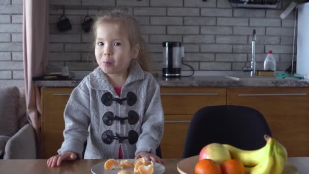 Criança sorridente feliz comendo frutas na cozinha — Vídeo de Stock