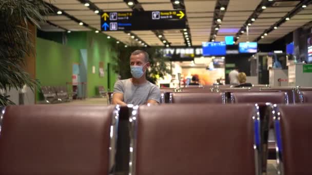 COVID-19 Seyahat. Maskeli bir adam boş bir havaalanında uçağını bekliyor. Coronavirus salgını, yeni normal seyahat. Uluslararası gezi — Stok video