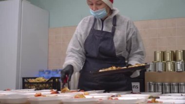 Fakir ve evsizler için Noel arifesi. Yemek bankası için kovid-19 yüz maskesi takan bir kadın ihtiyacı olanlara ücretsiz sıcak yemekler organize ediyor. COVID-19 salgınının ortasında gıda bankaları