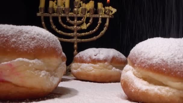 Menorah Chanuky a světla. Sufganiyot jsou smažené kuličky z kvasinkového těsta plněné jahodovým želé a silně oprášené prášeným cukrem. Vaření koblih — Stock video