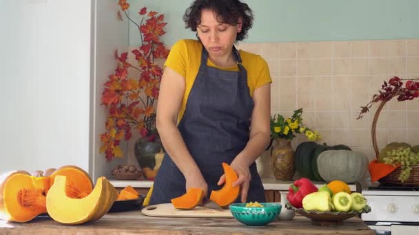 Mulher americana preparando torta de abóbora para o jantar de Ação de Graças. Férias de outono. Celebrar o Dia de Acção de Graças em casa com a família. Dona de casa corta abóbora laranja madura na cozinha. Festival da colheita — Vídeo de Stock