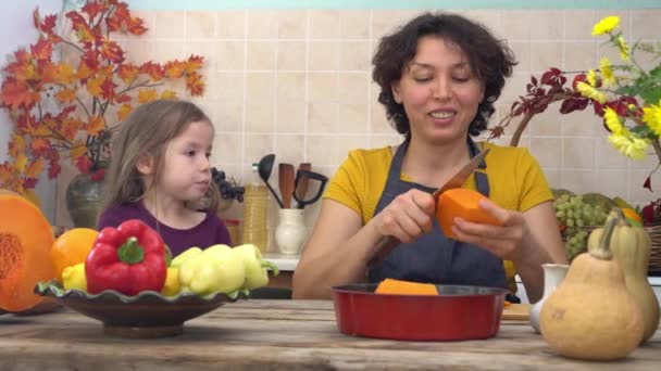 La hija feliz está ayudando a la madre a preparar pastel de calabaza festivo tradicional para la cena de Acción de Gracias. La familia americana celebra Acción de Gracias. Una chica aprende a hornear. Decoración casera caída — Vídeo de stock