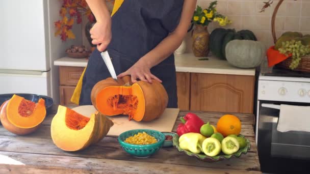 Thanksgiving holiday. Cooking pumpkin pie. Housewife cuts orange ripe pumpkin in the kitchen. Celebrating at home with family. Harvest festival. Fall home decoration — Stock Video