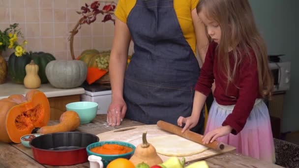 A filha feliz está ajudando a mãe a preparar a torta de abóbora festiva tradicional para o jantar de Ação de Graças. A família americana celebra o Dia de Acção de Graças. Uma rapariga aprende a fazer bolos. Decoração de casa de queda — Vídeo de Stock