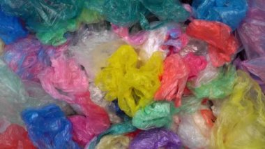 Bir sürü tek kullanımlık renkli plastik poşet büyük bir yığın halinde atılıyor. Atık geri dönüşüm tesisi. Plastik Paketleme Kirliliği. Çöp sahalarındaki plastik çöpler ve okyanus