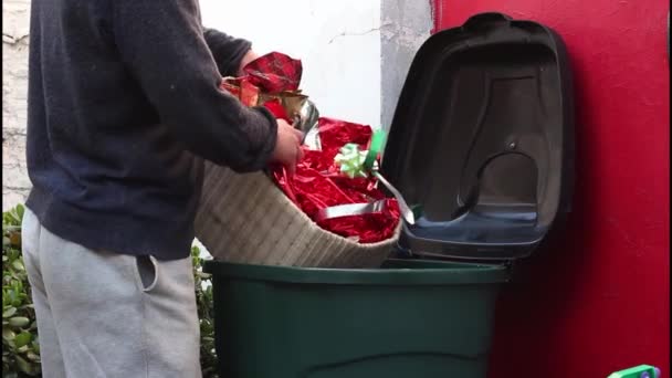 크리스마스 쓰레기, 휴일 쓰레기, 파티 플라스틱 쓰레기, 새해 쓰레기. 한 남자가 사용 한 선물 포장지를 쓰레기통에 던져 넣는다. 환경 오염 — 비디오