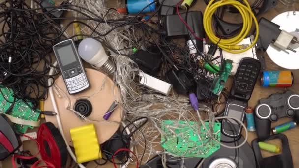 E-waste WEEE, бытовые опасные отходы. Отброшенные телефоны компьютеры батареи лампочки кабель проволоки и электроника. Используемые электрические приборы и устаревшее электронное оборудование — стоковое видео