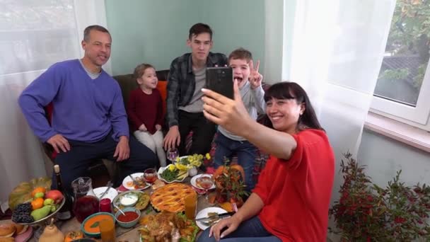 Το τηλεκοντρόλ. Μια ευτυχισμένη οικογένεια καλωσορίζει και συγχαίρει τους φίλους για τις διακοπές στο διαδίκτυο εξ αποστάσεως μέσω βιντεοκλήσης χρησιμοποιώντας ένα smartphone. Αυτοαπομόνωση και κλείδωμα. Διακοπές στο σπίτι — Αρχείο Βίντεο