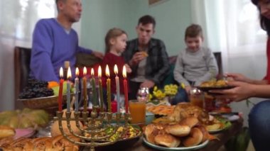 Menorah ışıklarını yakıyorum. Menora mumları. Hanuka bayramı yemeği evde, ailemle. Geleneksel Yahudi yemekleri masada - sufganiyot, latke, süzme peynir ve peynir yemekleri