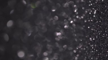 Siyah Parıltı Arkaplanı. Hafif bokeh, sihirli noel ışıkları. Sihirli toz, parlak doku, tatil ışıkları, uçan parçacıklar güzel bir bokeh oluşturur. Parlak Noel arkaplanı. Dikey Video