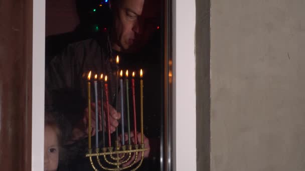 Janucá es el festival judío de ocho días, de invierno de luces. Una iluminación de menorá nocturna. Familia en casa, feliz padre e hija. Hanukkah en casa durante el encierro — Vídeo de stock