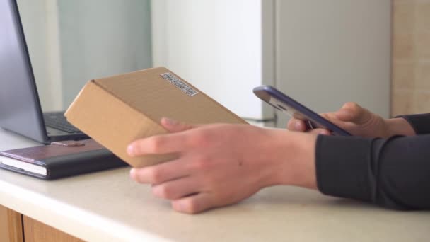 Attaching a QR code to delivery or package. A man using a smartphone and an application scans the QR code on the parcel box — Stock Video