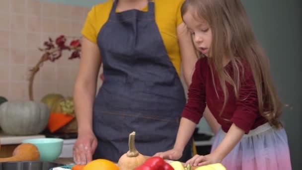 Mother and daughter cook pumpkin pie at home. Cooking together for a festive Thanksgiving dinner. A farmers family celebrates the harvest festival — Stock Video