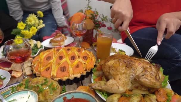 Hálaadási vacsora. Egy boldog többnemzetiségű család gyerekekkel egy ünnepi asztalnál. Anya pulykát vág. Hagyományos ételek az asztalon - sütőtök pite, sült burgonya, zsemle, zöldbab, kukorica. — Stock videók