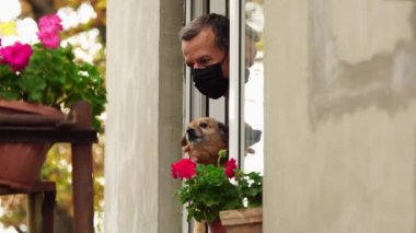 Covid-19 tecrit. Köpekli üzgün adam balkonda. Karantinada kendini izole etme, tecrit, evde kalma, sosyal mesafe