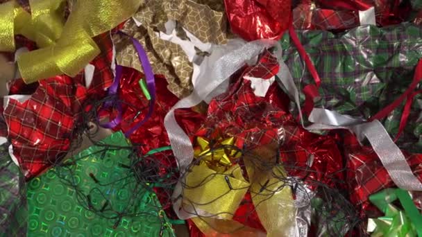 Kerst afval, vuilnis, vuilnis, rotzooi. Gebruikt inpakpapier, gebroken kerstboomverlichting, oude plastic decoraties, vakantiekaarten, aluminiumfolie, feestelijke plastic verpakking, linten — Stockvideo