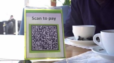 QR kodu, gerçek zamanlı temassız gerçek zamanlı ödeme. Uygulama için tarama yap. İş veya teknoloji konsepti: mağazada ödeme yapmak için QR kodunu taramak için akıllı telefon kullanan genç adam