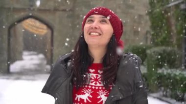 Mutlu genç bir kadın kar yağışına bakar. Noel 'in, karın ve kışın büyüsü. Şehirde kar yağışı