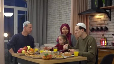 Asyalı Müslüman bir aile evde yemek yer, birlikte yemek yer. Oruç tuttuktan sonra iftar yiyeceği. Şenlikli yemek. Kutlama geleneği olan Arap yemekleri masada. Kurban bayramı.