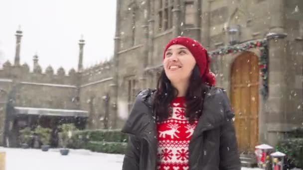 A smiling girl in an old European medieval town square during the Christmas holidays. Snow, Christmas tree and lights. Happiness, joy and smiles — ストック動画