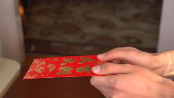 Um homem dá a uma criança um envelope vermelho hongbao com dinheiro. Ano Novo Chinês, Festival da Primavera ou Ano Novo Lunar — Vídeo de Stock
