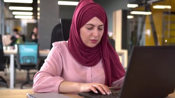Muzułmańska bizneswoman w hidżabie pracuje w biurze przy komputerze z międzynarodową ekipą — Wideo stockowe