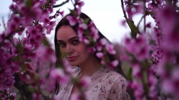 Giovane bella donna bruna in un giardino primaverile fiorito — Video Stock