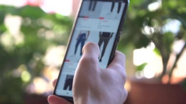 Evdeki Bir Adam İnternet Dükkanından Akıllı Telefon Satın Aldı. Müşteri Smartphone kullanarak çevrimiçi dükkandan kot pantolon sipariş ediyor. Çevrimiçi Alışveriş