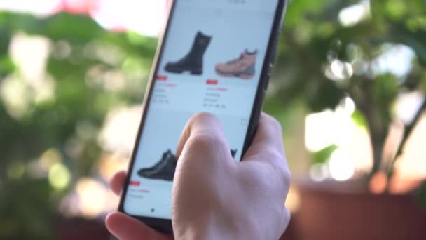 A Man at Home Using Smartphone Buys in Internet Shop. Le client commande des chaussures dans une boutique en ligne à l'aide d'un smartphone. Shopping en ligne — Video