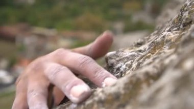 Tırmanışçıların elleri magnezyumla yakın çekim, yavaş çekim. Kadın zorlu bir uçuruma tırmanırken kenar tutuşu yapıyor. Magnezyum tebeşir havada süzülür kaya tırmanışçıları bir uçuruma tırmanırken