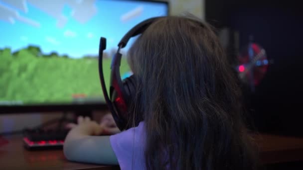 Un niño con auriculares juega un videojuego en línea en la computadora. El problema de la adicción a los juegos de ordenador en los niños. .. Entretenimiento durante el encierro — Vídeos de Stock