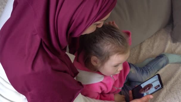 Muzułmańska matka i dziecko rozmawiają przez video z mężczyzną. Zostań w domu Ramadan. Gratulacje online z okazji wakacji w Eid al-Adha — Wideo stockowe