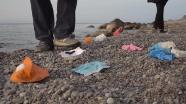 Covid-19 plastik atık, kullanılmış yüz maskesi, okyanusta eldivenler. Çöp toplayıcısı ya da gönüllü, deniz kıyısını temizliyor. Çevre kirliliği