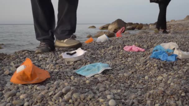 Resíduos de plástico Covid-19, máscara facial usada, luvas no oceano. Coletor de lixo ou voluntário limpa a praia. Poluição ambiental — Vídeo de Stock