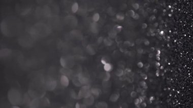 Siyah Parıltı Arkaplanı. Işık bokeh, sihirli tatil ışıkları. Parlak doku, uçan parçacıklar güzel bir bokeh oluşturur. Parlak şenlikli dikey zemin
