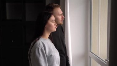 Evde çocuğu olan üzgün evli bir çift pencereden dışarı bakar.