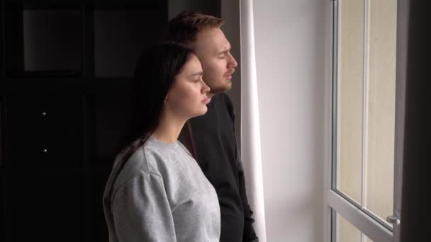 Een verdrietig getrouwd stel met een kind thuis kijkt uit het raam — Stockvideo