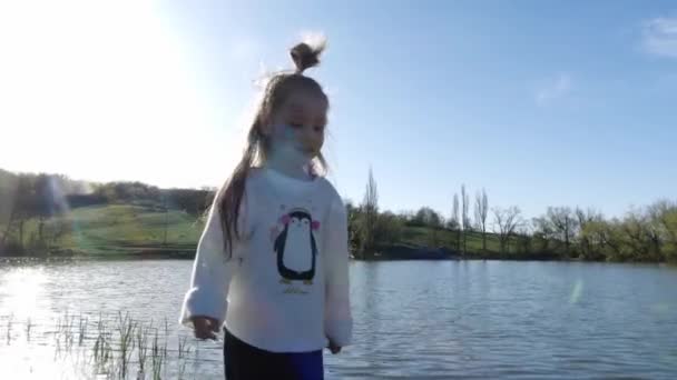 Uma menina bonita com sorrisos aquagrim. Dia ensolarado na natureza, margem do lago — Vídeo de Stock