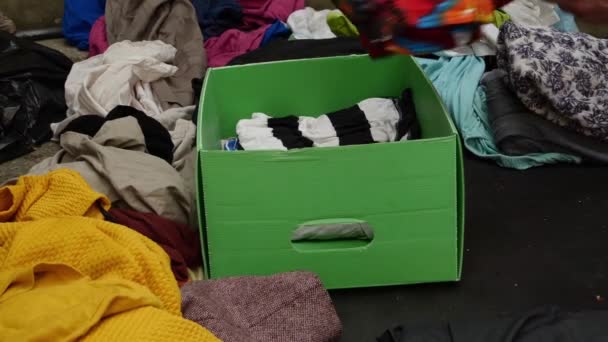 Une personne met des vêtements usagés dans une boîte de don pour les réutiliser — Video