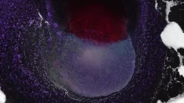Koyu mor kırmızı renkler mürekkep ve parlak parçacıklar makro. Akışkan sanat.