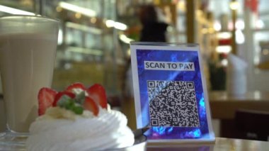 QR kodu ile ücretsiz ödeme yap. QR kod tarama uygulaması. İşletmeler için dokunulmaz dijital ödeme seçeneği. Sahilde açık bir kafede oturan bir adam. Yüksek kalite 4k görüntü