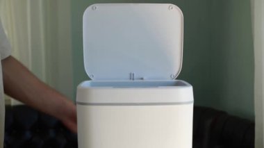 A man throws broken fluorescent light bulb in a regular trash bin. Electronics, toxic waste. Environmental pollution. Contactless Smart Touch Trash Can. High quality 4k footage