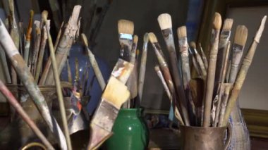 Artists art tools in the art studio. Oil painting in creative workroom. Brushes, paints, palette, canvas, easel, vintage frames. High quality 4k footage