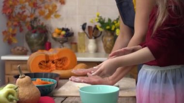 Küçük kız mutfakta annesine yardım ediyor. Anne ve kızı evde hamuru birlikte hazırlıyorlar. Çocuk elleri merdaneyle yemek pişirir. Yüksek kaliteli FullHD görüntüler