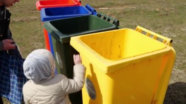 Plastik, kağıt, metal, cam atık kutuları. Baba çocuğa çöpü ayırmayı öğretir. Yüksek kalite 4k görüntü