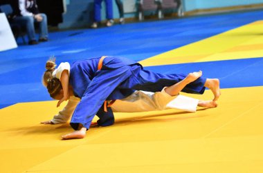 Kimonolu iki kız judoka tatamide yarışıyor. 
