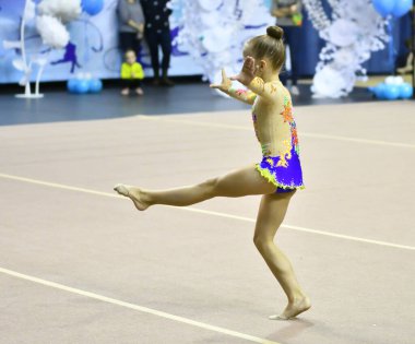 Kız, ritmik jimnastikte zorunlu bir program yürütüyor. 